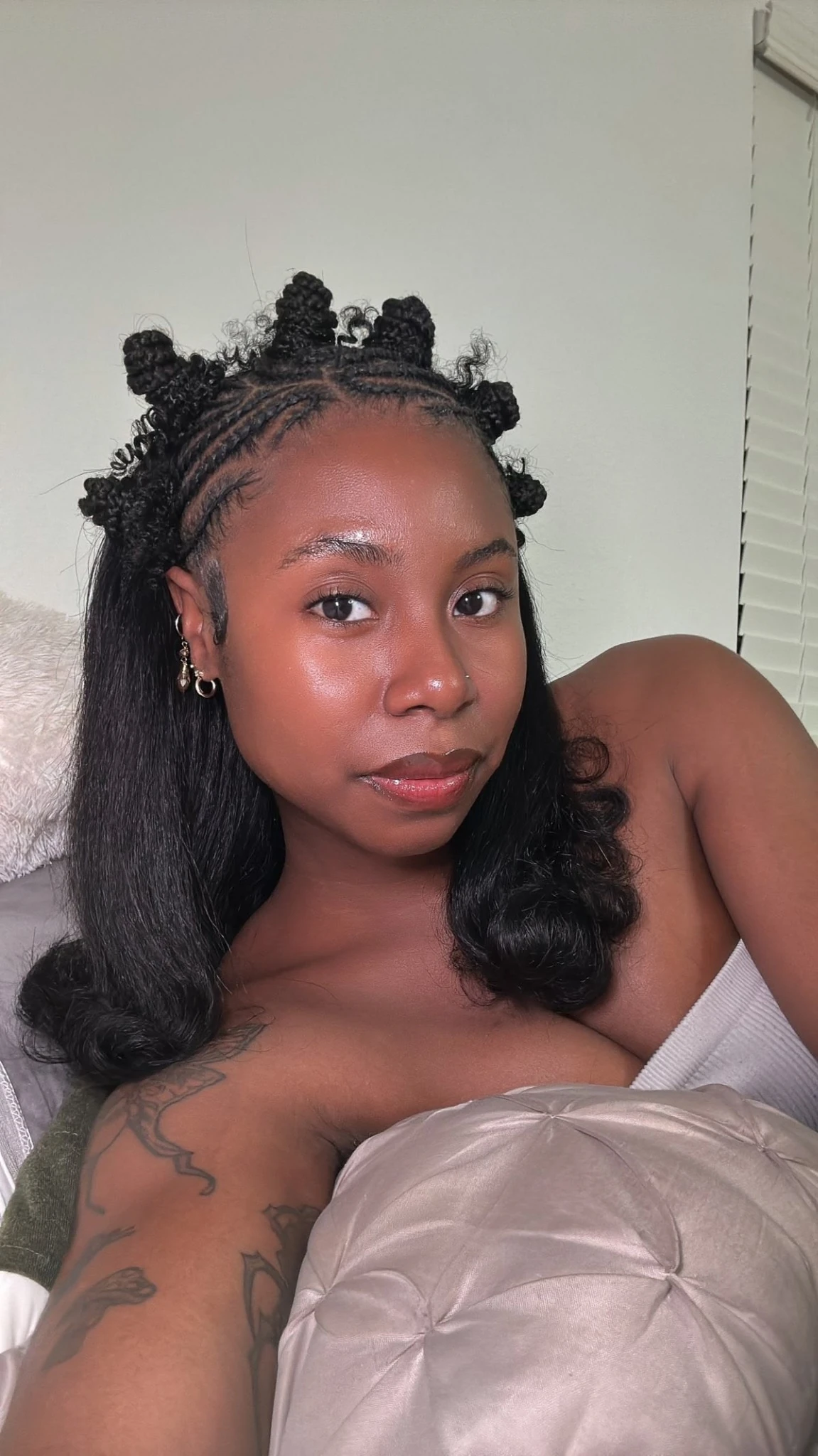 Coiffure Bantu Knots half-up avec plusieurs chignons tressés devant et longueurs noires libres derrière